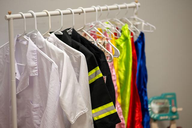 Dress-up clothes on a rail, including a firefighter jacket and white coats