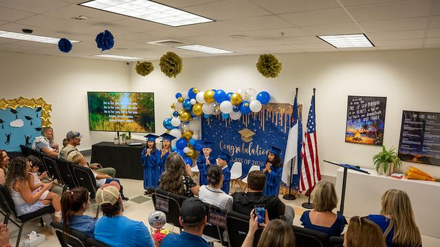 Families seated in rows watching the graduates at the front of the room