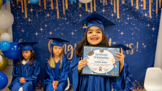 A happy graduate holding a certificate of graduation beside classmates