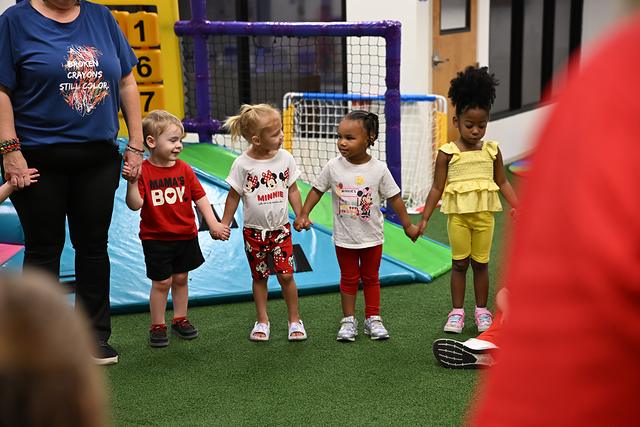 Children holding hands in a line in the indoor play area