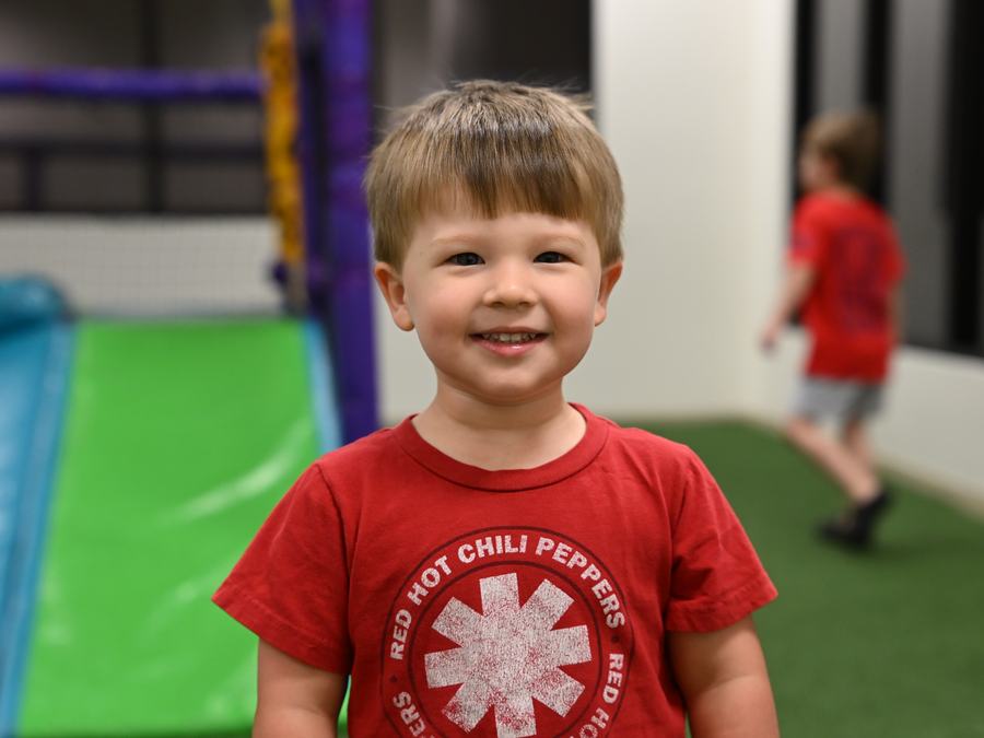 A smiling boy in a red T-shirt in the indoor play area