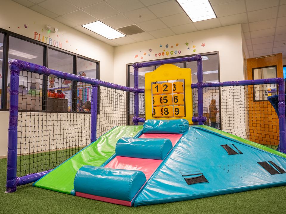 The indoor play room with a soft climbing ramp and a number board