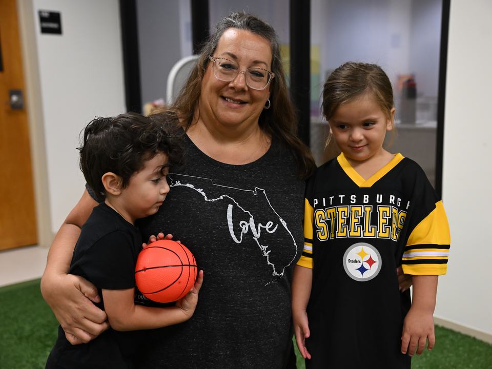 A teacher hugging two children in the play room